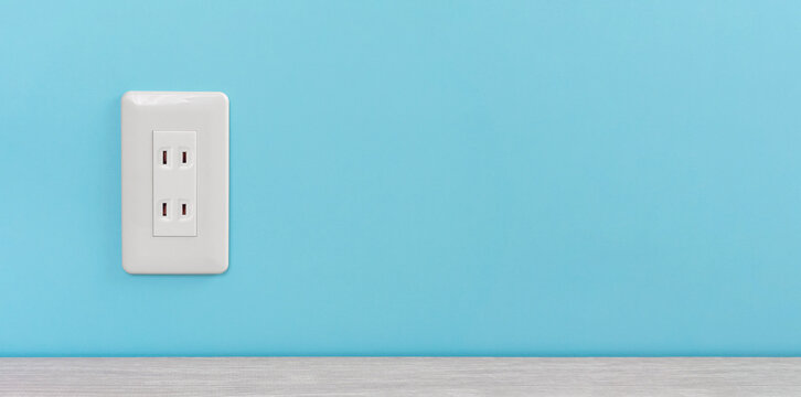 white electric outlet mounted on light blue wall. 水色の壁に取り付けられた白いコンセント