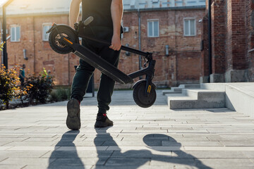 Folded Electric scooter in mans hand on urban street © Oleksandr Kozak