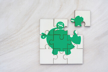 Top view jigsaw puzzle a piggy bank shape puzzle in the public park, Saving money or loan to...