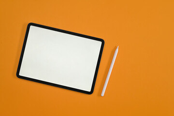 Top view with empty screen of digital tablet, tablet and stylus pen on yellow studio background.