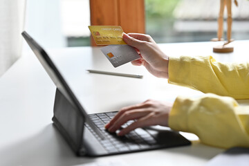 Selective focus on female's hand holding credit cards and other hand touch on digital tablet.