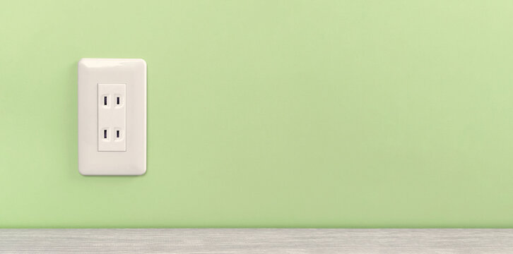 white electric outlet mounted on light green wall. 緑色の壁に取り付けられた白いコンセント