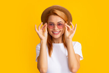 Beautiful woman in stylish sunglasses and straw hat on yellow background.