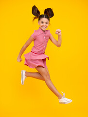 Happy teenager, positive and smiling emotions of teen girl. Teenager girl jumping. Full length of her she playful preteen teenager girl having fun and jumping isolated on yellow background.