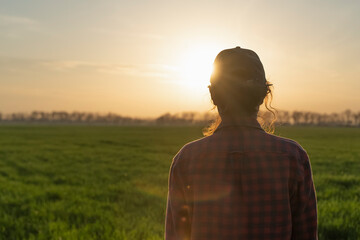 Farmer woman inspects the fields. Portrait on girl agronomist view from the back. Organic smart farming industry. 
