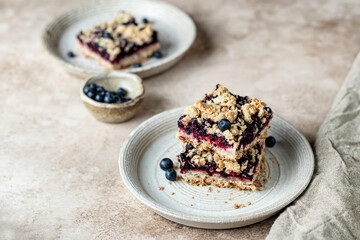 Homemade blueberry crumble bars on a plate on beige background. Healthy breakfast composition, text space