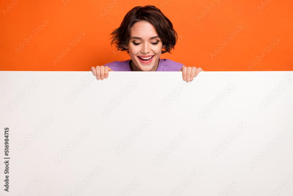 Poster Photo of sweet excited lady wear violet sweatshirt looking white poster empty space isolated orange color background