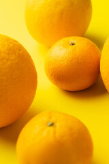 Close up view of fresh tangerines and oranges on yellow background.