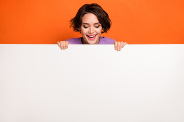 Photo of sweet excited lady wear violet sweatshirt looking white poster empty space isolated orange...