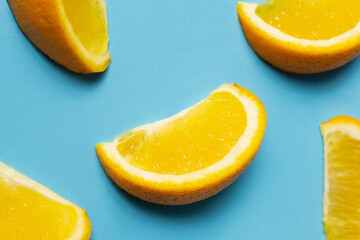 Naklejka na ściany i meble Close up view of juicy pieces of orange on blue background.
