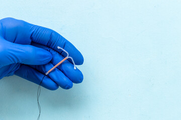 Doctor gynecologist holding intrauterine contraceptive device. T-shaped copper contraceptive - obrazy, fototapety, plakaty