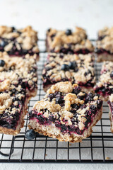 Homemade blueberry crumble bars on baking rack close up on white background, healthy snack for...