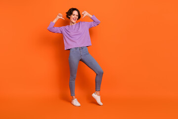 Fototapeta na wymiar Full length photo of confident funny girl dressed purple pullover pointing thumbs herself empty space isolated orange color background