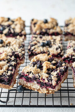 Homemade blueberry crumble bars on baking rack close up on white background, healthy snack for school