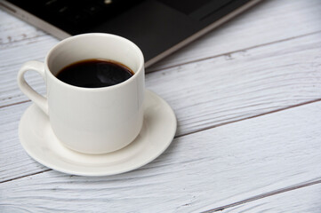 Coffee cup and laptop on wooden table with customizable space for text or ideas. Copy space