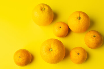 Top view of fresh oranges and mandarins on yellow background.