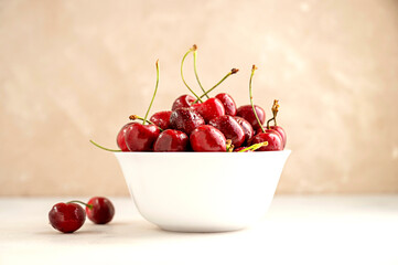 Fresh red cherries in white bowl, on neutral background. Summer delicious fruit.