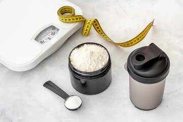 Whey protein powder in jar and scales. Fitness and gym food diet