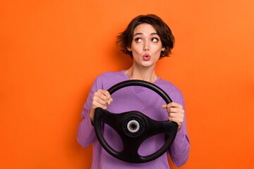 Photo of impressed shocked lady wear violet sweatshirt riding car looking empty space isolated orange color background