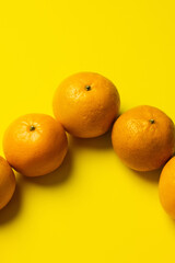 High angle view of tangerines in peel on yellow background.