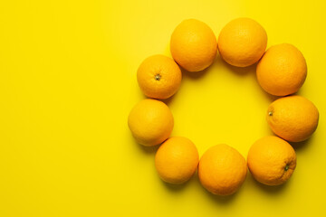 Top view of oranges in frame shape on yellow background.