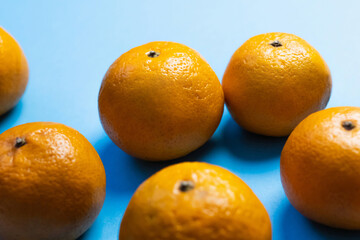 Close up view of ripe tangerines on blue background.