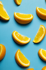 Fototapeta na wymiar Top view of pieces of oranges with shadow on blue background.