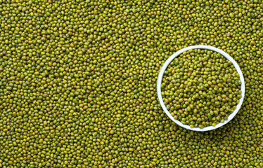 ceramic plate with raw mung beans on a mung beans background close-up top view.