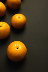 Top view of fresh tangerines on black background.