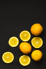 Top view of natural whole and cut oranges isolated on black.