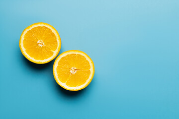 Top view of cut oranges with shadow on blue background with copy space.