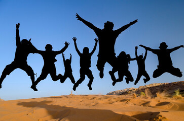 Silhouttes of people jumping in the desert of wadi rum