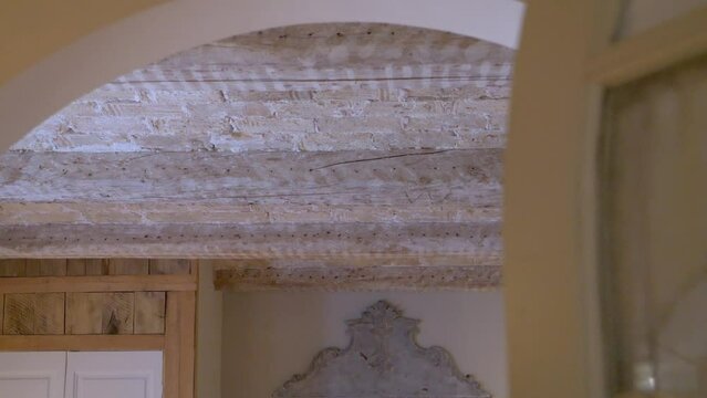 Entering rustic house from rounded door with wood beam support roof in southern France, Dolly in reveal shot