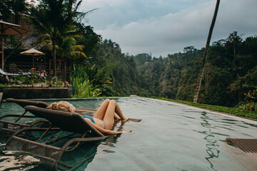 Young woman lounging at the pool side in Bali