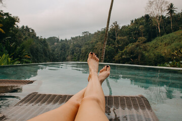 Young woman's legs lounging at the pool side