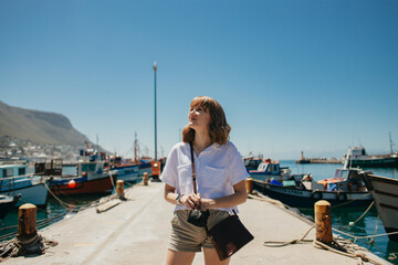 Young blonde woman exploring harbour - obrazy, fototapety, plakaty