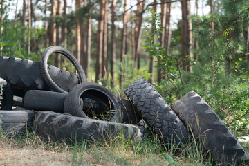 Fototapeta na wymiar pile of car tires on the side of the road in the forest on the foreground blurred trees in the background