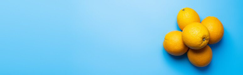 Top view of tropical oranges on blue background, banner.