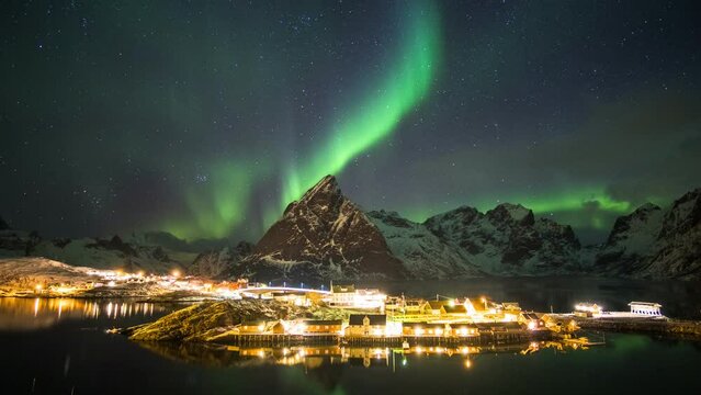 Time lapse of aurora borealis dancing on mountains with fishing village.