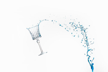 Blue liquid spillig from a pattered square beverage glass