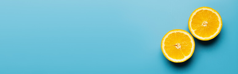 Top view of natural cut orange on blue background, banner.
