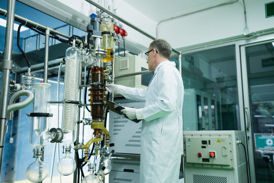 Caucasian expert marijuana researcher in lab uniform is working in the cannabis laboratory. Biochemical male scientist with motivation checking quality control in the process of CBD oil extraction.