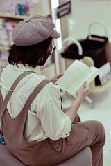 Asian women reading book by bookshelf in bookstore. Hobbies, leisure and education concept.