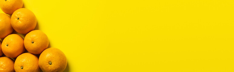 Flat lay with tangerines in peel on yellow background, banner.