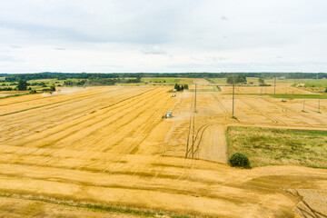 Aerial view of agricultural parcels of different crops. Hay bale fields and farmlands of Lithuania. Harvesting machinery or equipment.