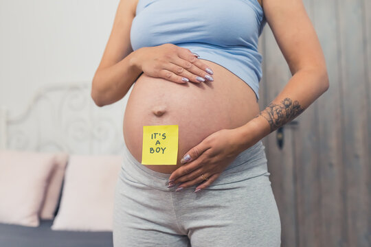 pregnant woman with a sticky note saying boy on her belly, closeup . High quality photo