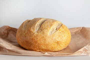 A round loaf of sourdough wheat bread lies on a paper craft bag
