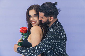 Flower surprise. Dark-haired bearded handsome Cuban man embracing his beloved young wife from the...