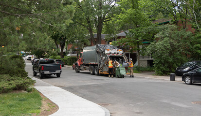 Camion recyclage et employé ramassant un bac sur une rue