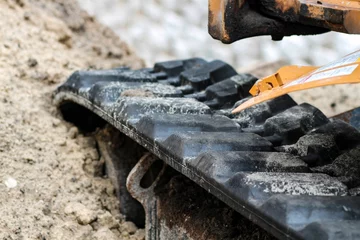 Zelfklevend Fotobehang High angle shot of an excavator track rubber tires during construction © Priscilla Pasos/Wirestock Creators